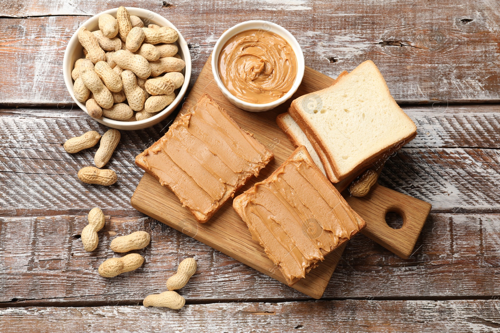 Photo of Delicious sandwiches with peanut butter and fresh nuts on wooden table, flat lay