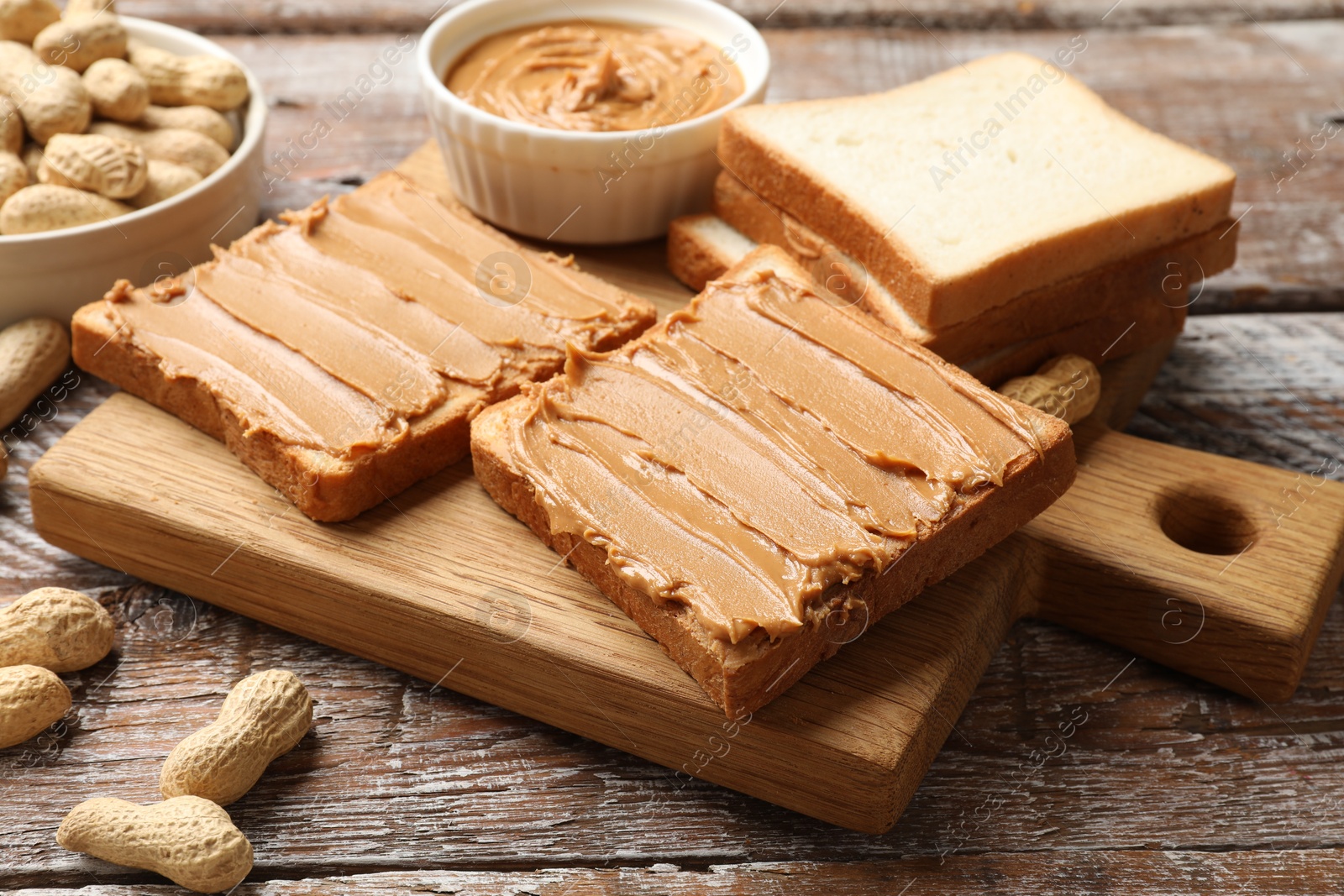 Photo of Delicious sandwiches with peanut butter and fresh nuts on wooden table, closeup