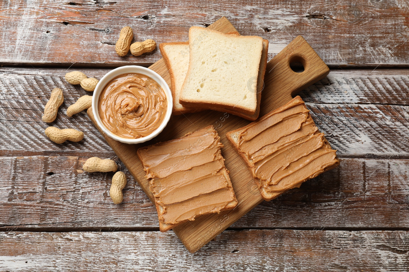 Photo of Delicious sandwiches with peanut butter and fresh nuts on wooden table, top view