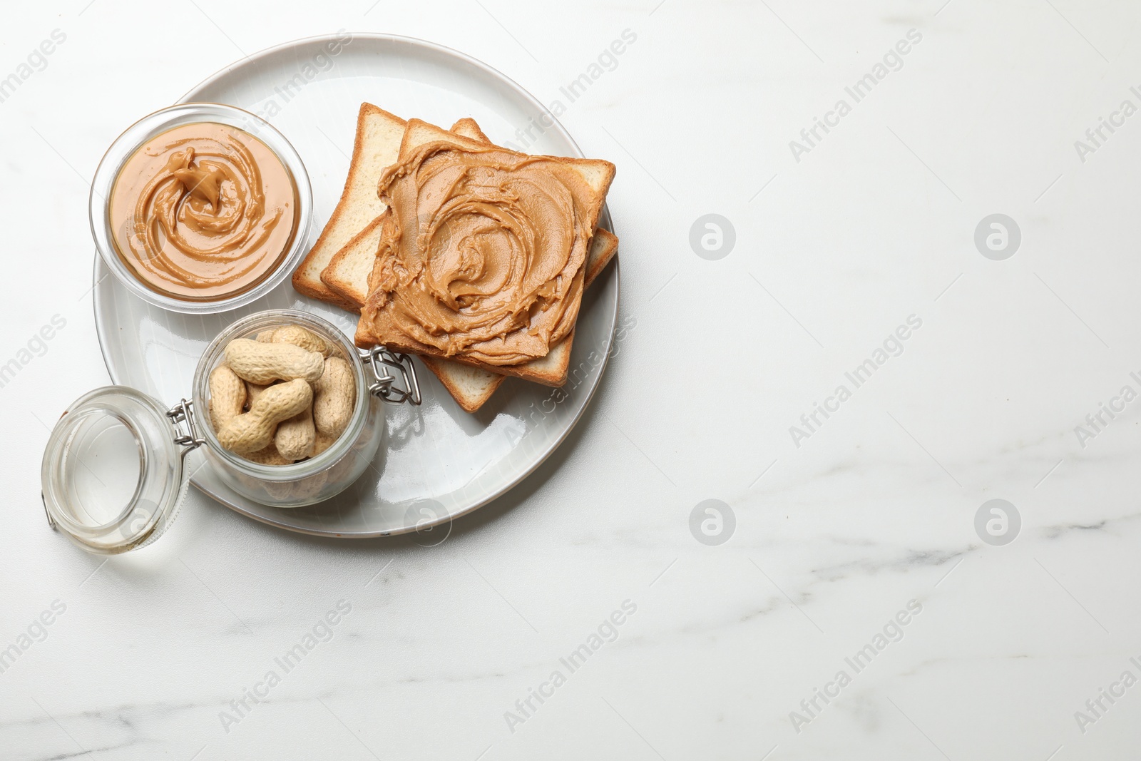 Photo of Delicious sandwich with peanut butter and fresh nuts on white marble table, top view. Space for text