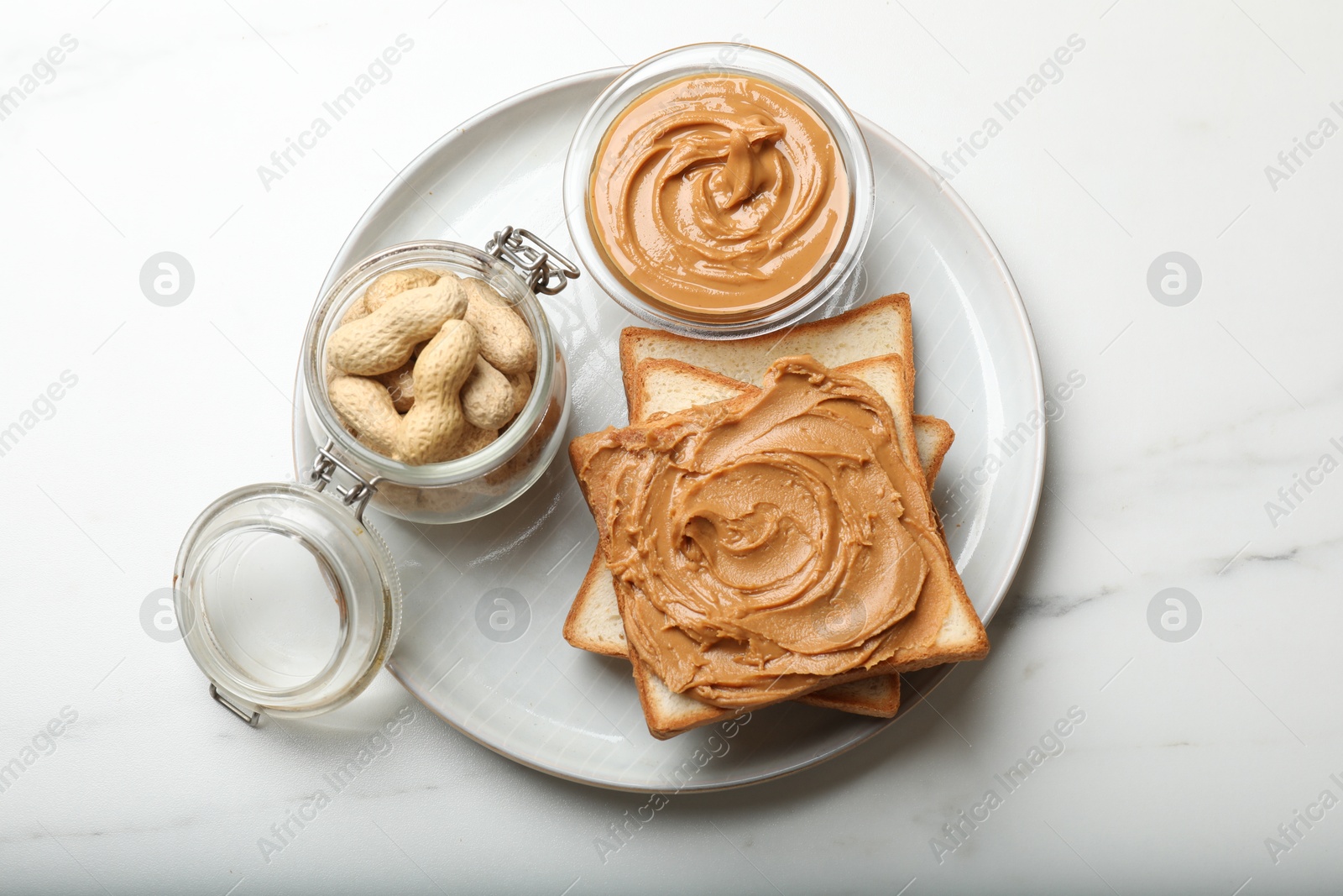 Photo of Delicious sandwich with peanut butter and fresh nuts on white marble table, top view