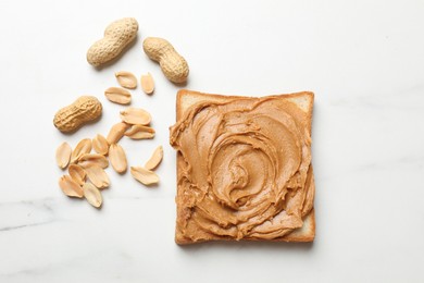 Photo of Delicious sandwich with peanut butter and fresh nuts on white marble table, flat lay