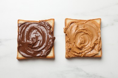 Photo of Delicious sandwiches with peanut butter and chocolate paste on white marble table, top view