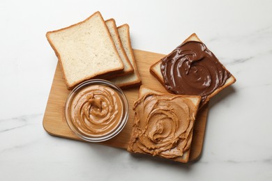 Delicious sandwiches with peanut butter and chocolate paste on white marble table, top view