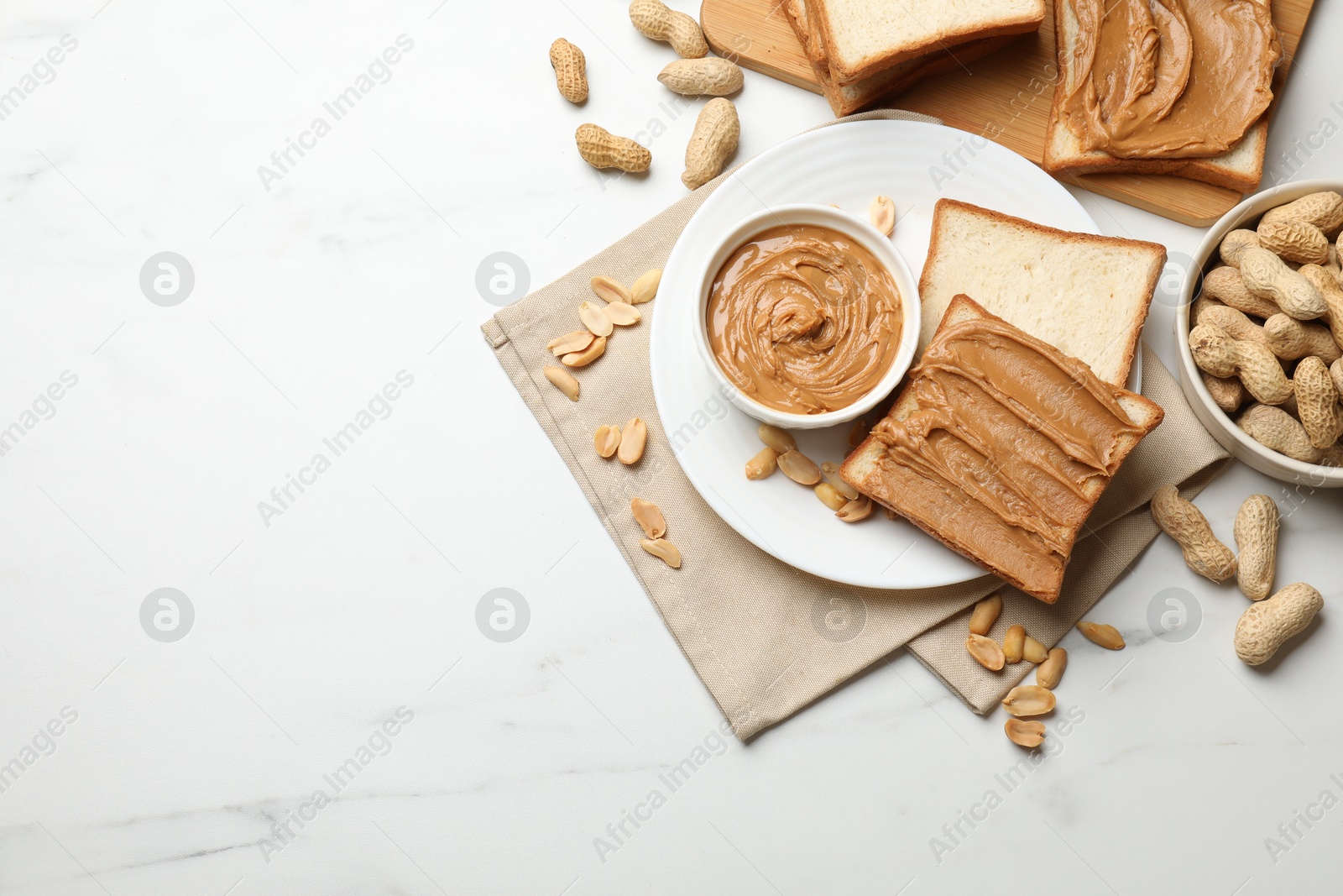 Photo of Delicious sandwiches with peanut butter and fresh nuts on white marble table, flat lay. Space for text