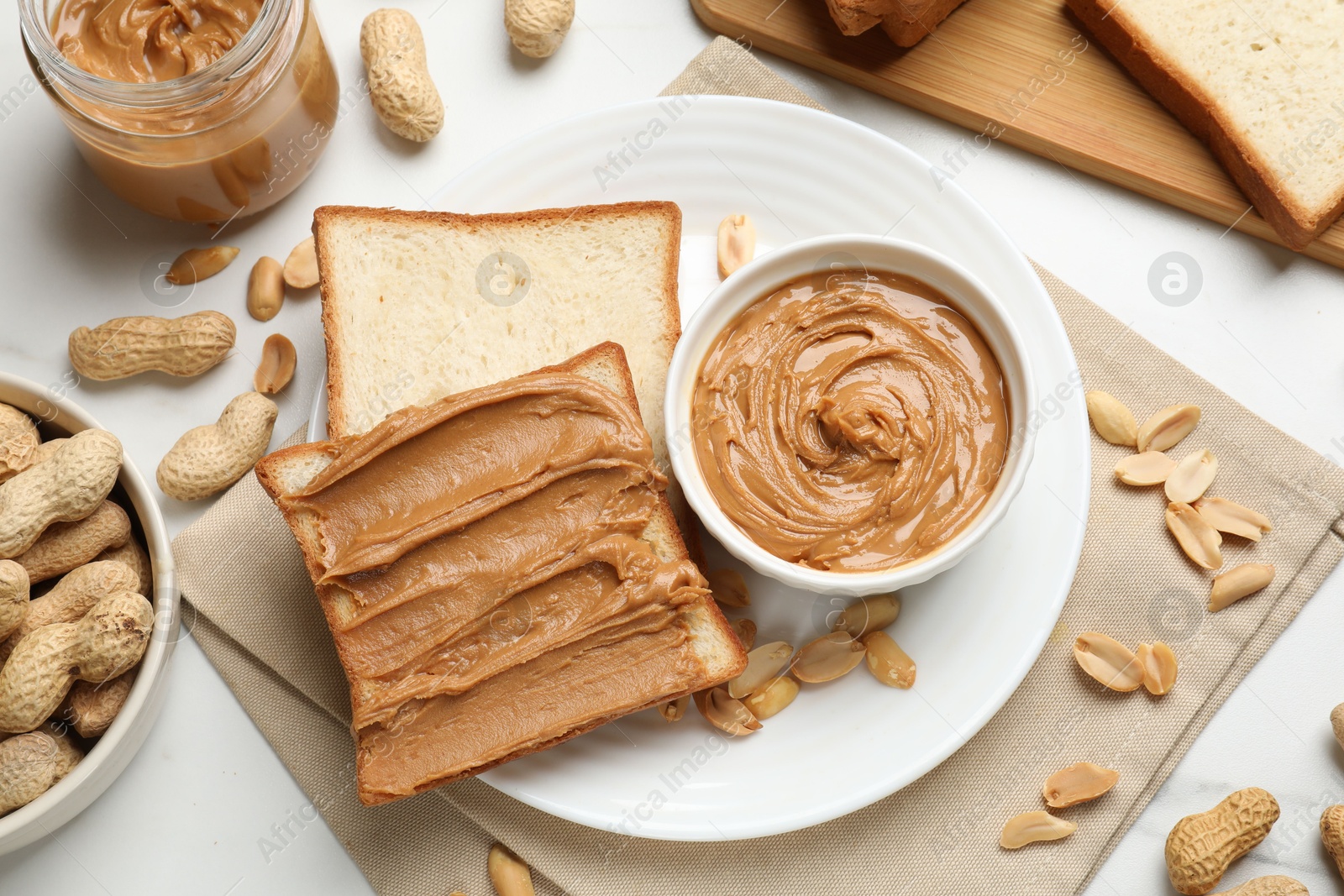 Photo of Delicious sandwich with peanut butter and fresh nuts on white table, flat lay