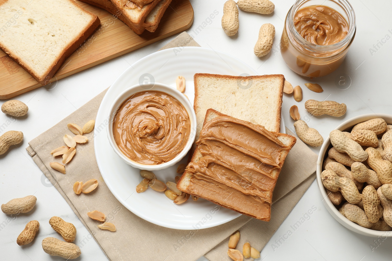 Photo of Delicious sandwich with peanut butter and fresh nuts on white table, flat lay