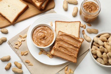 Photo of Delicious sandwich with peanut butter and fresh nuts on white table, flat lay