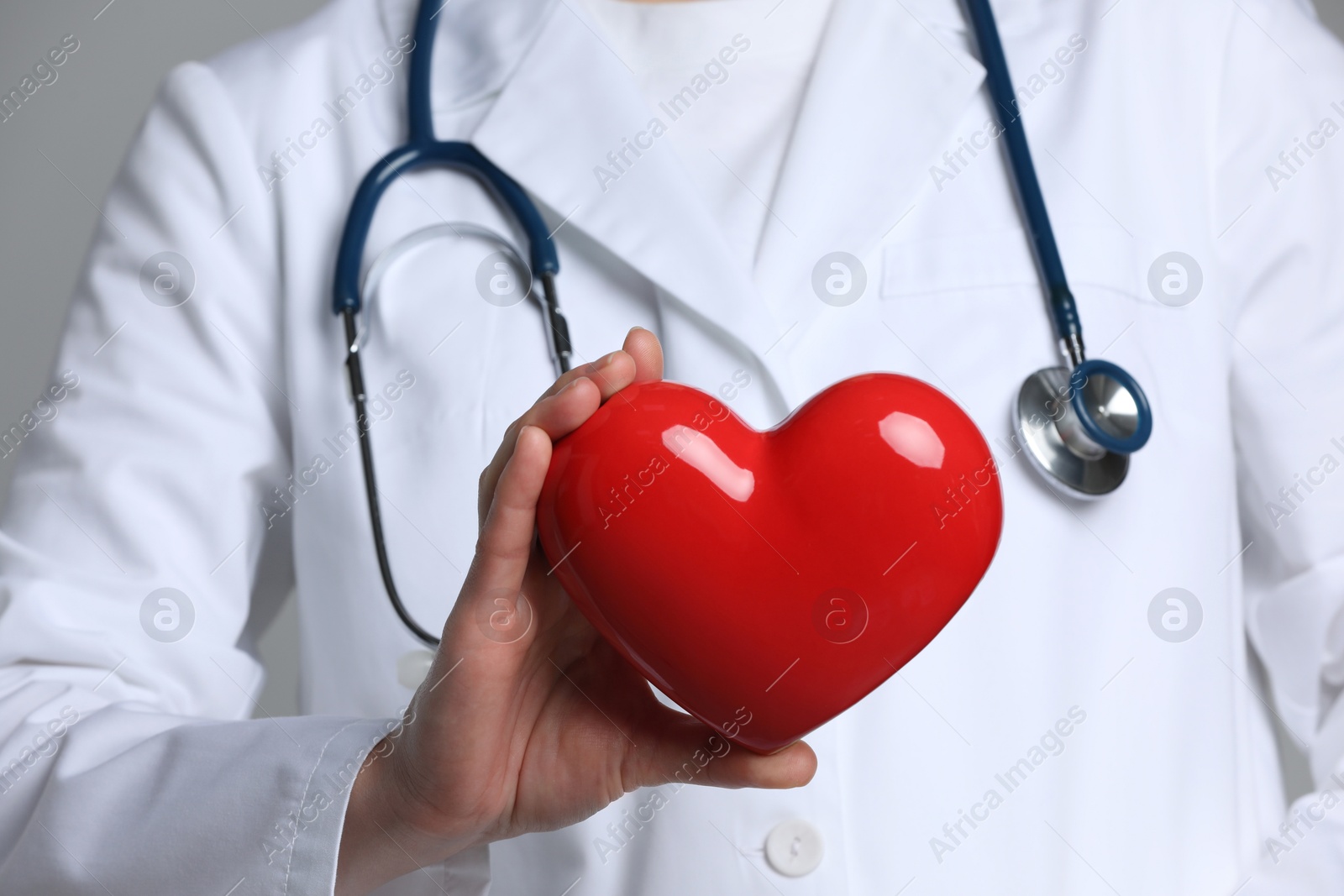 Photo of Doctor with red heart on grey background, closeup