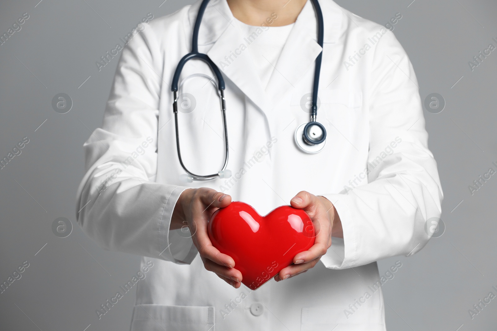 Photo of Doctor with red heart on grey background, closeup