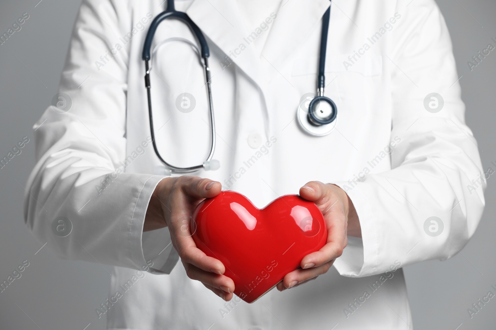 Photo of Doctor with red heart on grey background, closeup