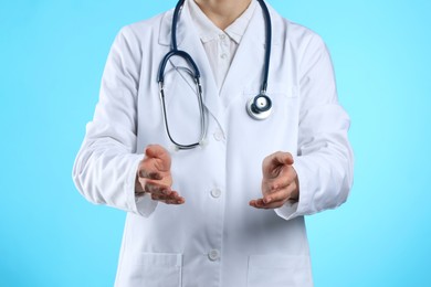 Doctor holding something on light blue background, closeup