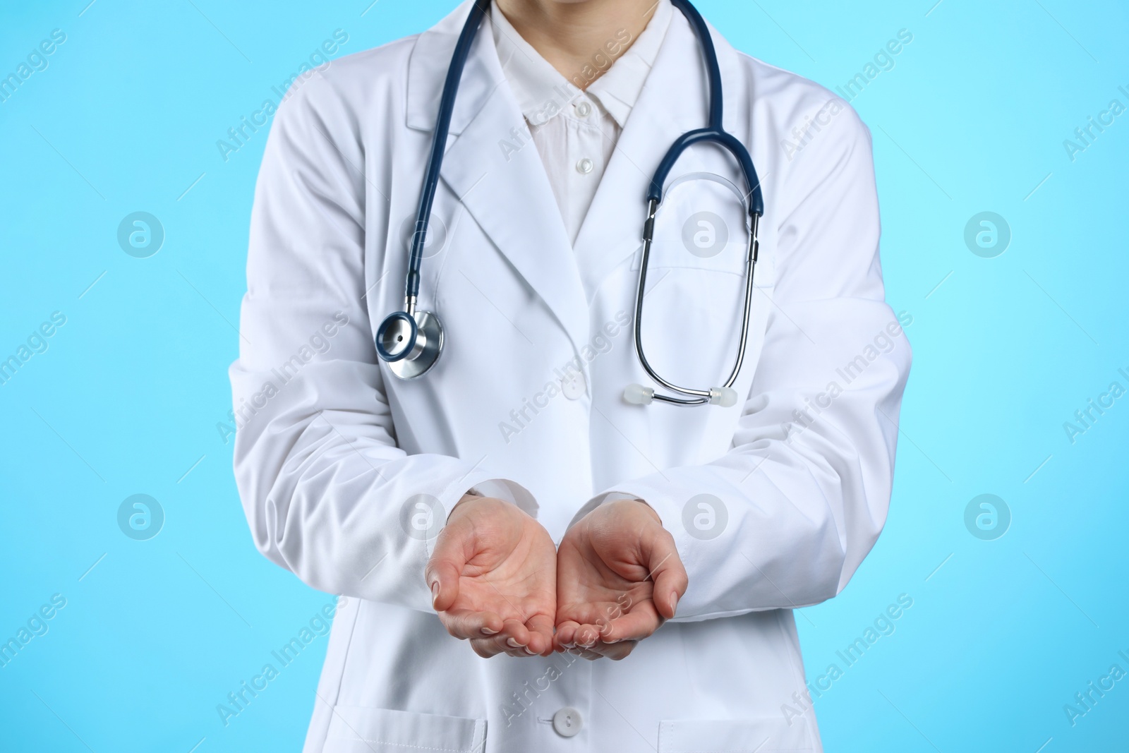 Photo of Doctor holding something on light blue background, closeup