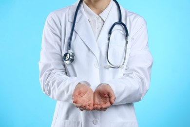 Doctor holding something on light blue background, closeup