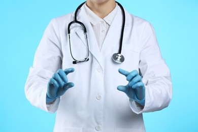 Doctor holding something on light blue background, closeup