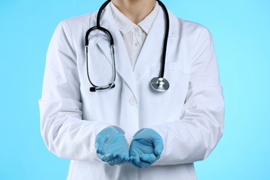 Photo of Doctor holding something on light blue background, closeup