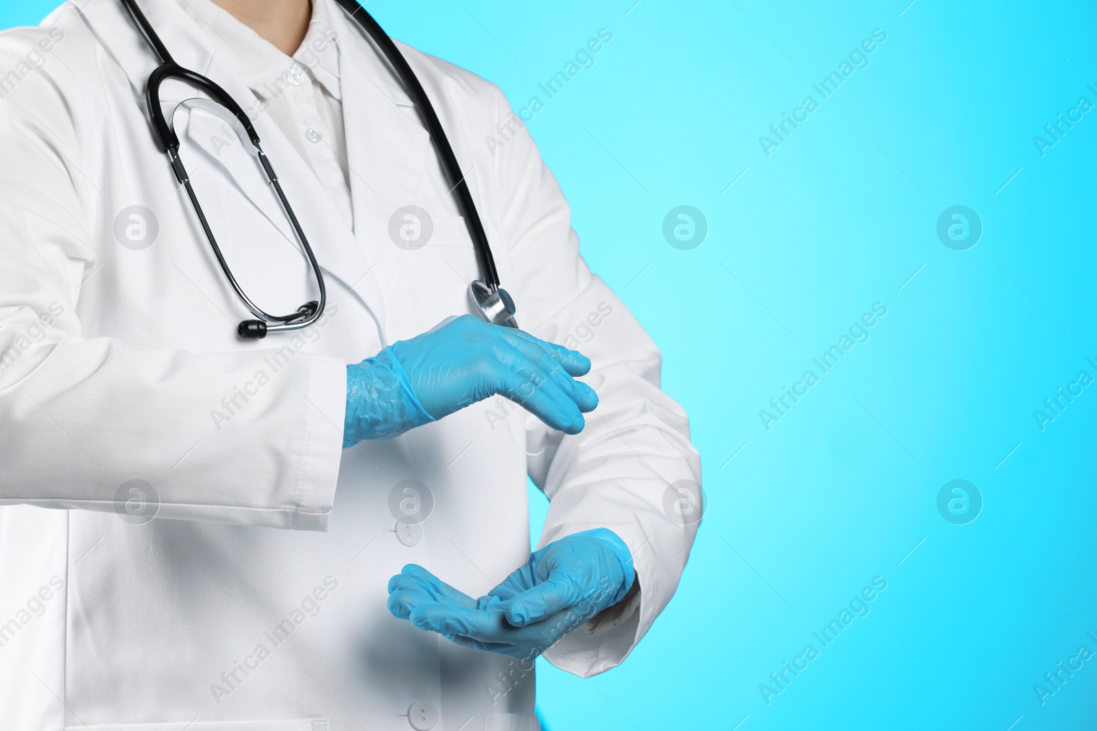 Photo of Doctor holding something on light blue background, closeup. Space for text