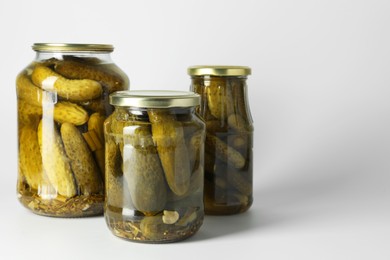 Photo of Pickled cucumbers in jars on light background. Space for text