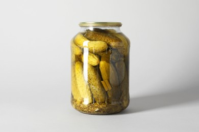 Pickled cucumbers in jar on light background