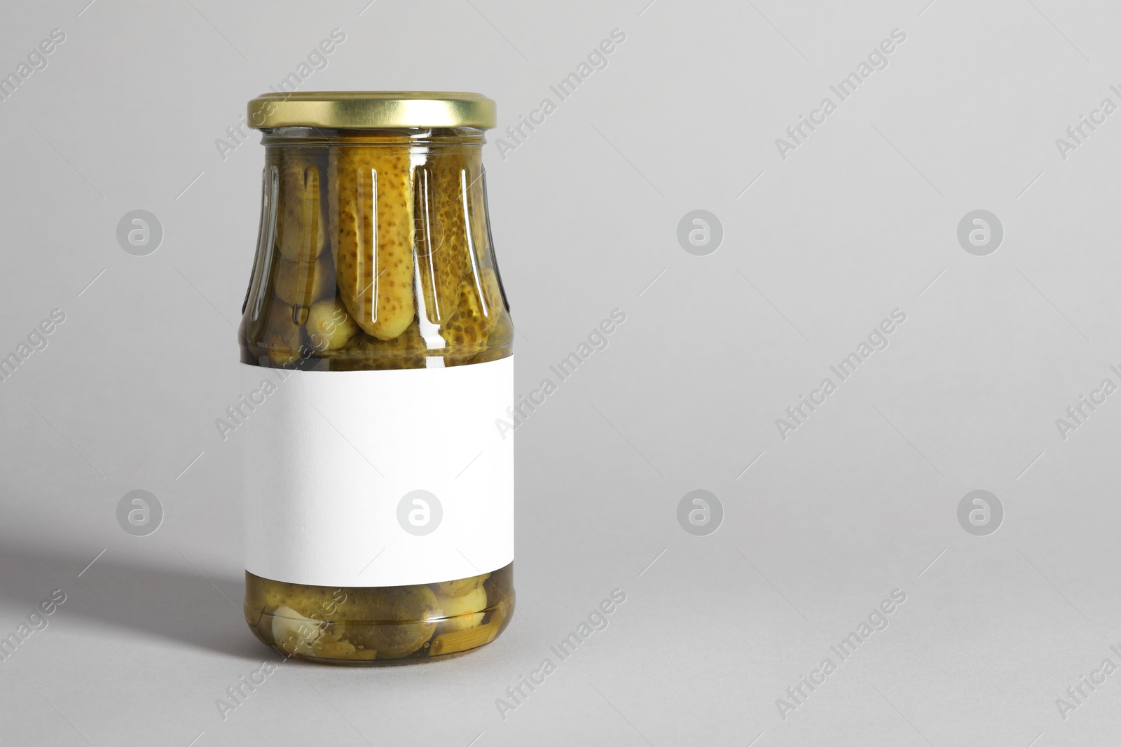 Photo of Pickled cucumbers in jar on light background. Space for text