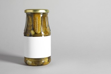 Pickled cucumbers in jar on light background. Space for text