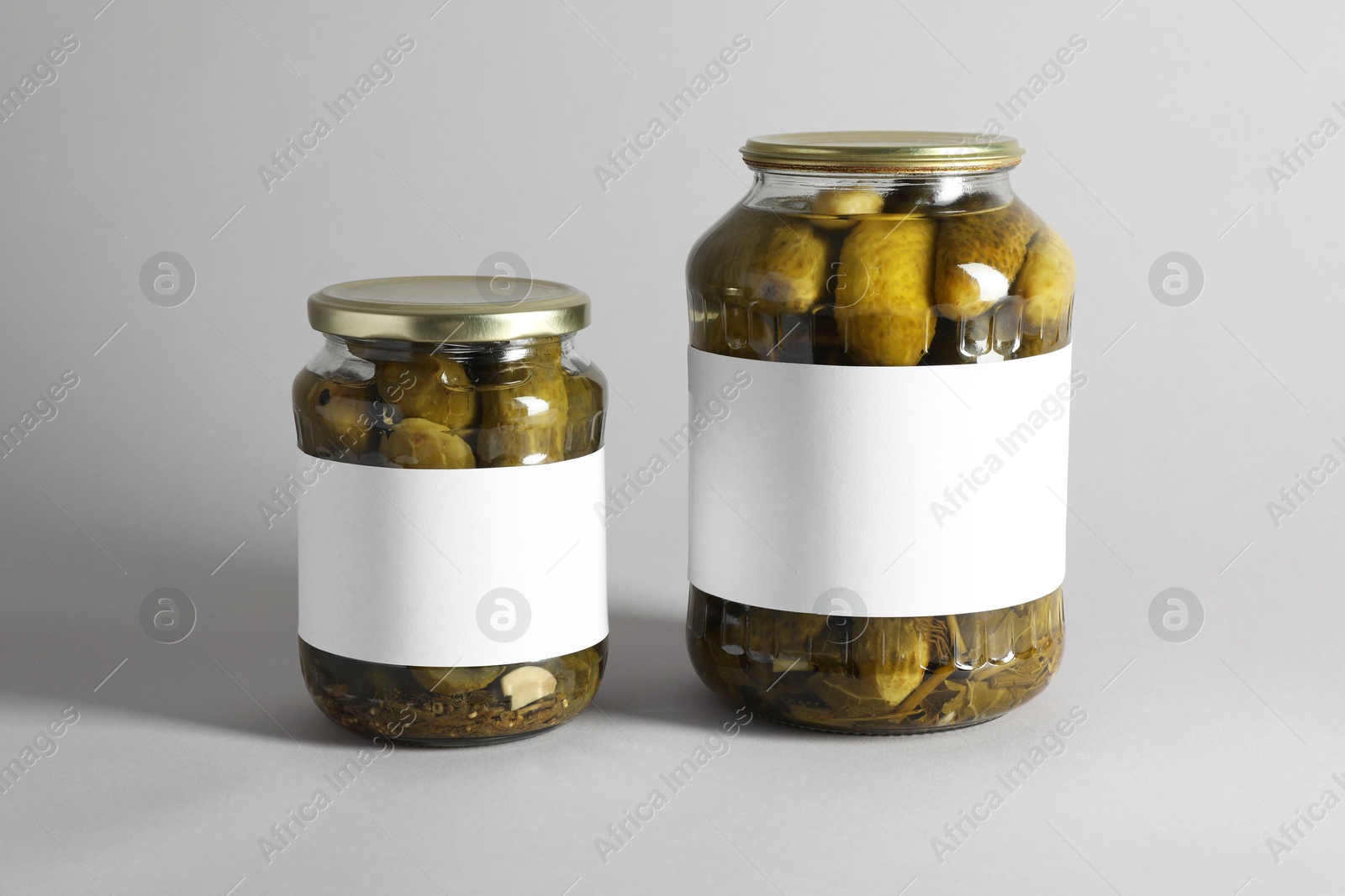 Photo of Pickled cucumbers in jars on light background