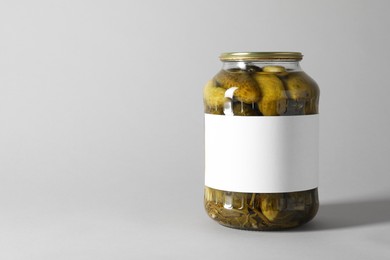 Pickled cucumbers in jar on light background. Space for text