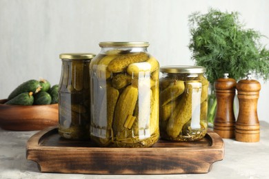 Pickled cucumbers in jars on grey table