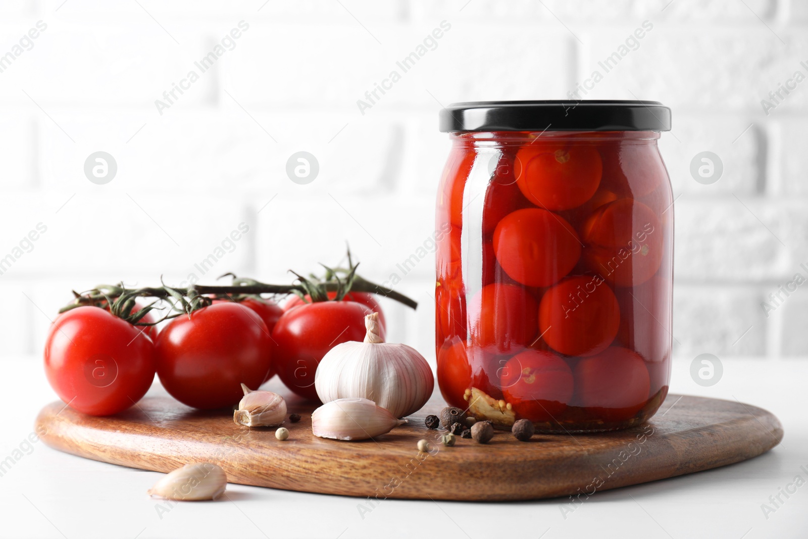 Photo of Tasty pickled tomatoes in jar, fresh vegetables and spices on white table