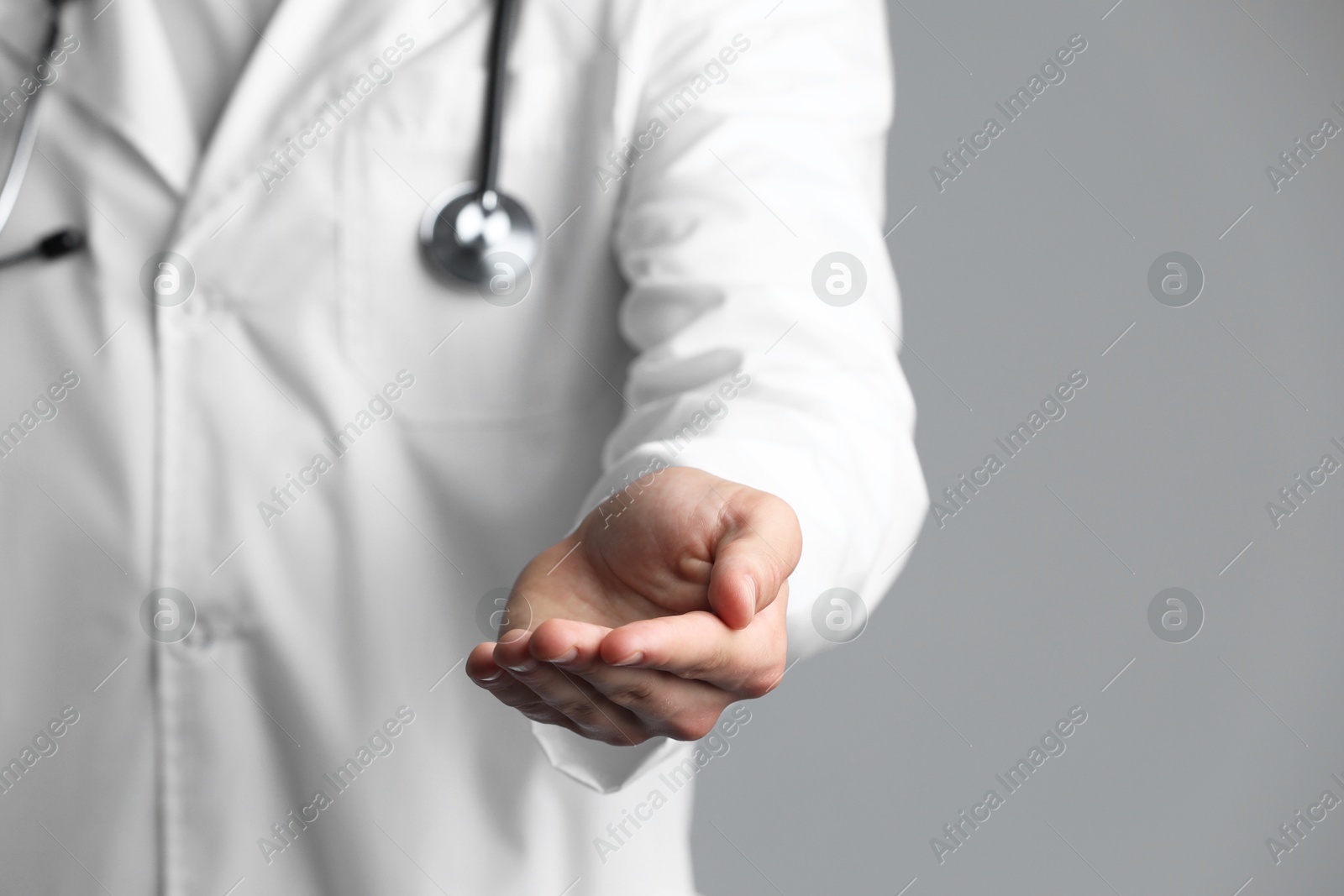 Photo of Doctor holding something on grey background, closeup