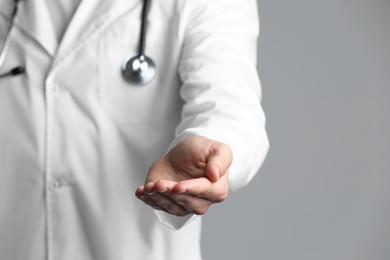 Doctor holding something on grey background, closeup