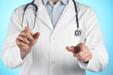 Photo of Doctor pointing at something on light blue background, closeup