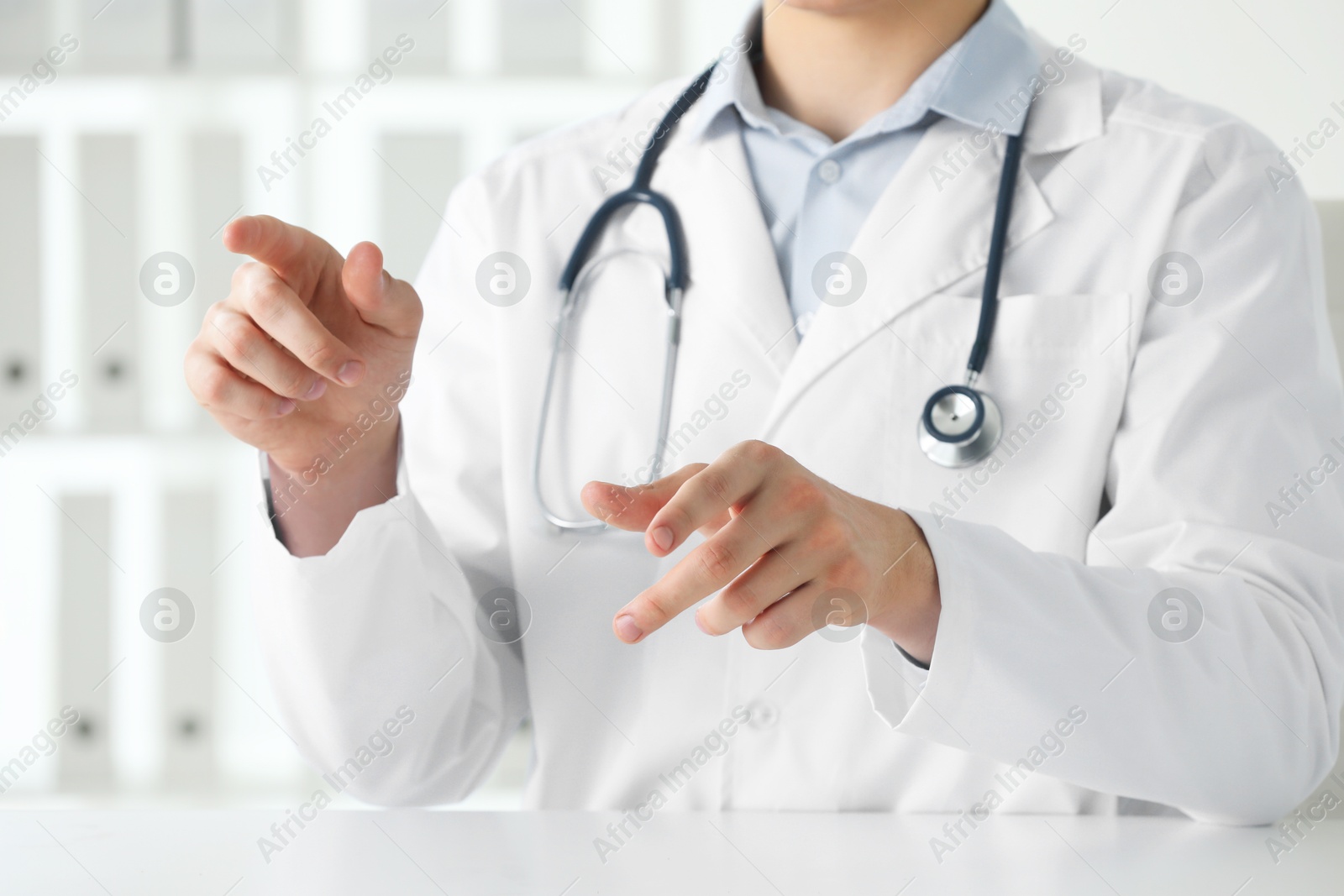 Photo of Doctor pointing at something at white table in clinic, closeup