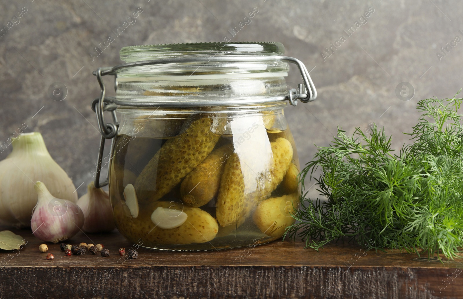 Photo of Pickled cucumbers in jar and spices on wooden table