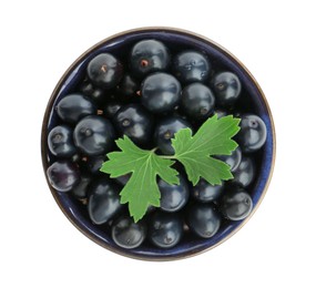 Bowl of ripe blackcurrants and green leaves isolated on white, top view