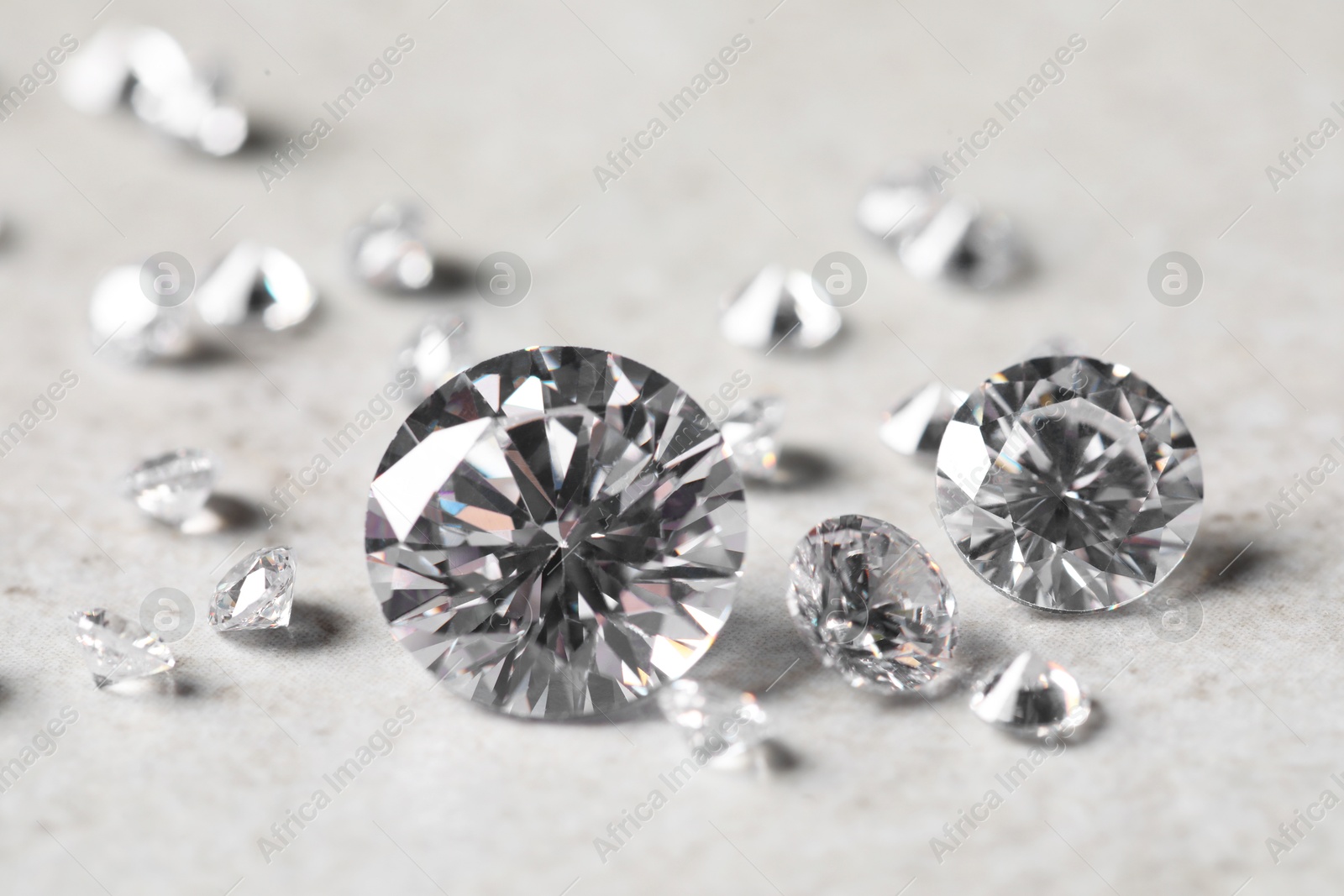 Photo of Many beautiful shiny diamonds on light background, closeup