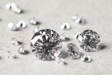 Many beautiful shiny diamonds on light background, closeup