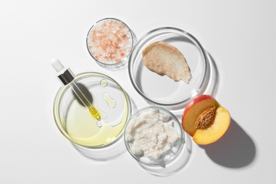 Photo of Petri dishes with different cosmetic products and peach on white background, flat lay