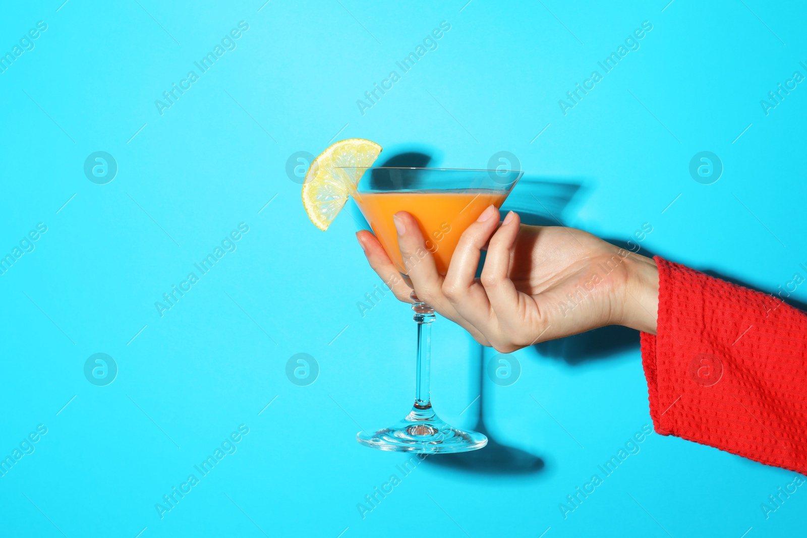 Photo of Woman with glass of refreshing cocktail on light blue background, closeup