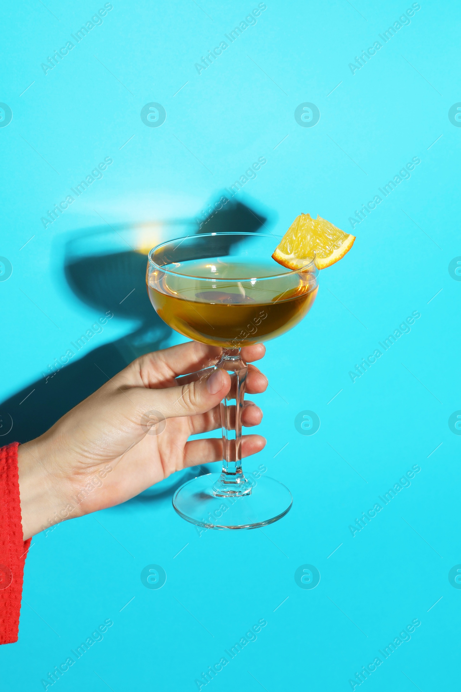 Photo of Woman with glass of refreshing cocktail on light blue background, closeup