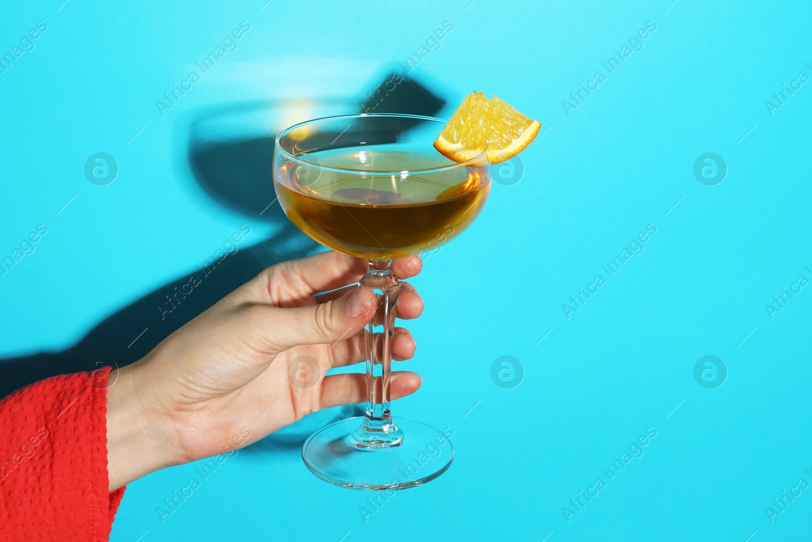 Photo of Woman with glass of refreshing cocktail on light blue background, closeup