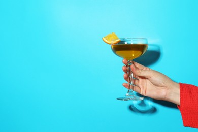 Photo of Woman with glass of refreshing cocktail on light blue background, closeup