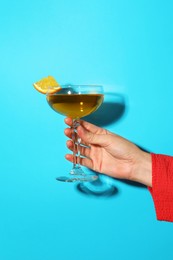 Photo of Woman with glass of refreshing cocktail on light blue background, closeup