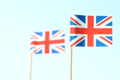 Photo of Small paper flags of United Kingdom on light blue background, selective focus