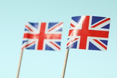 Photo of Small paper flags of United Kingdom on light blue background, selective focus