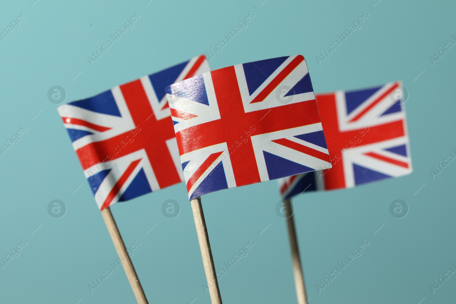 Photo of Small paper flags of United Kingdom on light blue background, selective focus