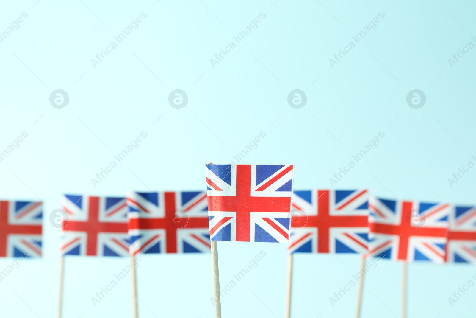 Photo of Small paper flags of United Kingdom on light blue background, selective focus. Space for text