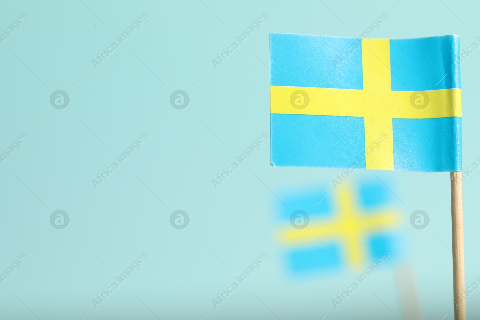 Photo of Small paper flags of Sweden on light blue background, selective focus. Space for text