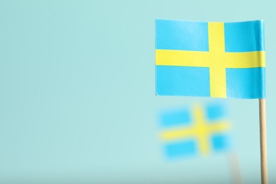 Photo of Small paper flags of Sweden on light blue background, selective focus. Space for text