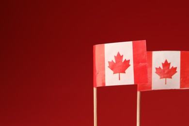 Photo of Small paper flags of Canada on red background, selective focus. Space for text